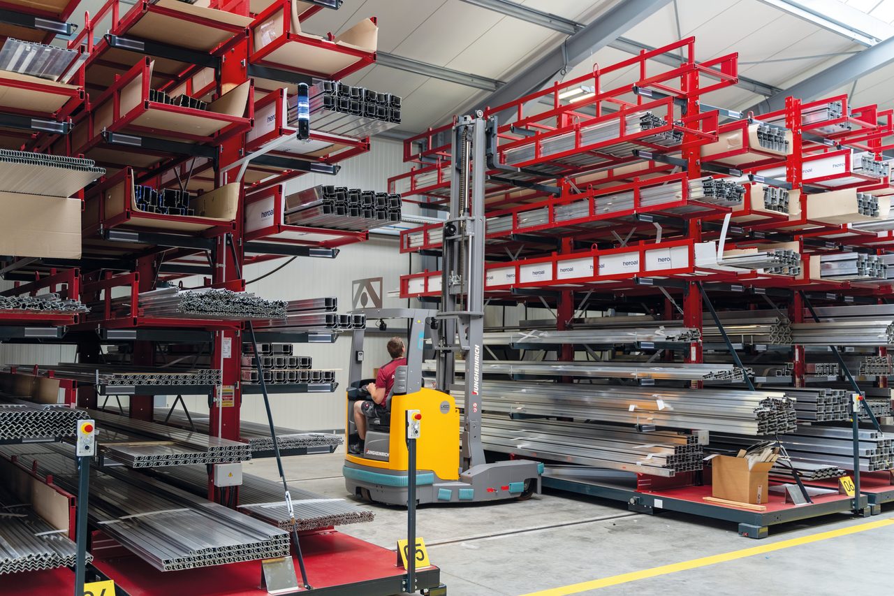 Profillager von EBE mit roten Kragarmregalen voller Aluminiumprofile, davor ein Seitenstapler